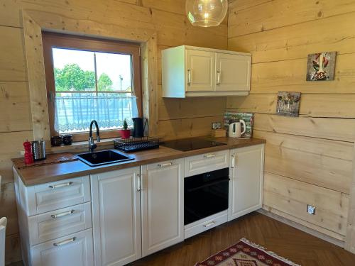 a kitchen with white cabinets and a sink and a window at Słoneczna Chata z Bali in Lądek-Zdrój