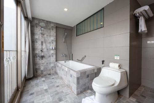 a bathroom with a toilet and a bath tub at Le Thatluang D'oR Boutique Hotel in Vientiane