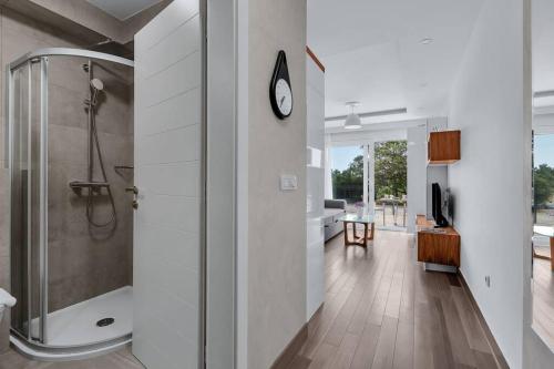 a bathroom with a shower and a clock on the wall at Brotis - StudioApartment in Promajna
