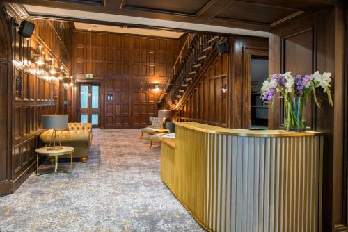 a lobby with wood paneling and stairs with a vase of flowers at Lilleshall House & Gardens and Lilleshall National Sports Centre in Telford