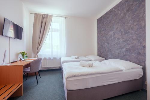a hotel room with two beds and a desk and a desk at Národní dům Podbořany in Podbořany