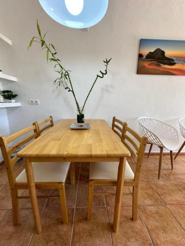 een houten tafel met stoelen en een vaas met een plant erop bij AT Espalmador Formentera rustick in Es Pujols