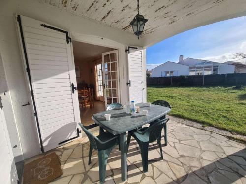 un patio avec une table et des chaises sur un porche dans l'établissement Maison confort proche mer avec jardin, WiFi et équipements pratiques - FR-1-224C-144, à Saint-Hilaire-de-Riez