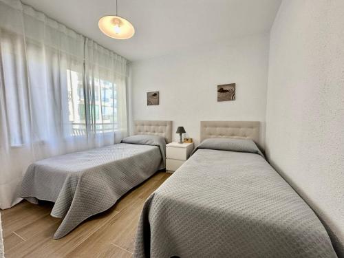 a bedroom with two beds and a window at Apartamento Rancho Suizo in Platja d'Aro