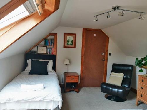 1 dormitorio en el ático con 1 cama y 1 silla en Nest Holiday Home Central Callander, Trossachs Self-catering en Callander