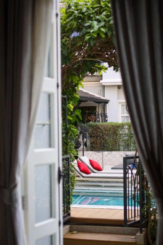 a door leading to a pool with pillows on a bed at Le Thatluang D'oR Boutique Hotel in Vientiane