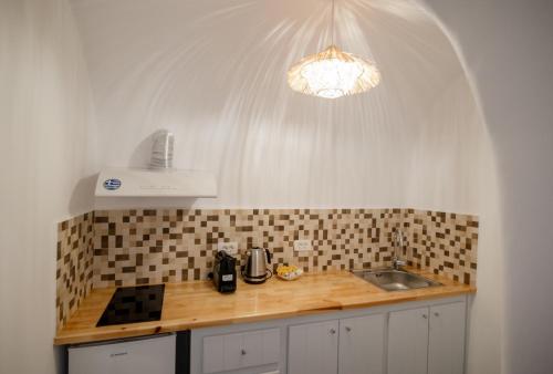a kitchen with a counter with a sink and a light at Sun Angelos Oia - Luxury Cave Suites in Oia