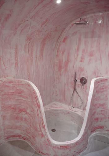 a pink marble room with a bath tub in it at Sun Angelos Oia - Luxury Cave Suites in Oia