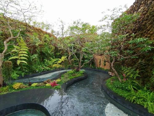a stream in a garden with trees and plants at Rarin Villas in Chiang Mai