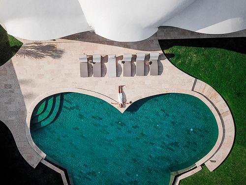 タバナンにあるThe Cloud Beachfront Villa Tabananのハート付きスイミングプールのオーバーヘッドビュー
