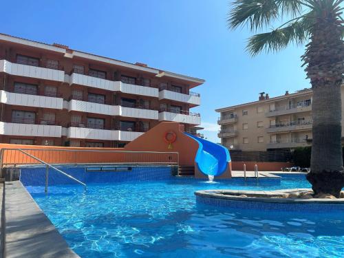 a swimming pool with a slide in front of a hotel at Alojamientos familiares Sa Gavina Estartit, Principal in L'Estartit