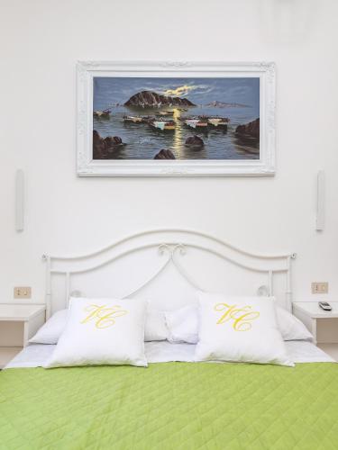 a bedroom with a white bed with a painting on the wall at Villa Cristina - De Vivo Realty Piano di Sorrento in Piano di Sorrento