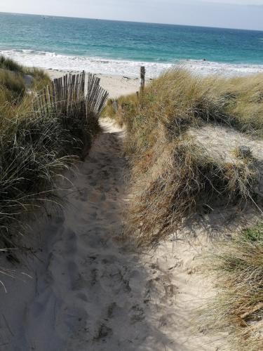 un camino de arena a la playa con el océano en L'air Breton, en Goulven
