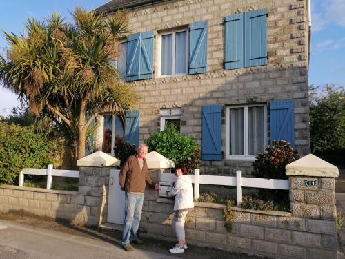 un hombre y una mujer parados frente a una casa en L'air Breton, en Goulven