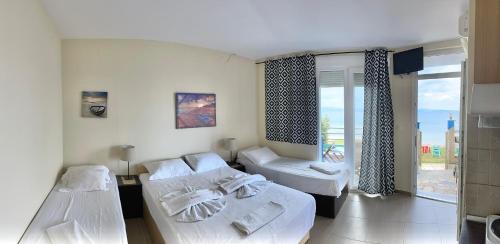 a hotel room with two beds and a balcony at Rooms Elena in Nea Potidaea