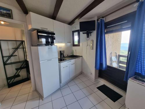une cuisine avec un réfrigérateur blanc et une fenêtre dans l'établissement Studio rénové 2 pers - Balcon Sud - Animaux admis - FR-1-393-80, à Saint-Michel-de-Chaillol