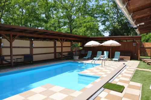 a swimming pool with umbrellas and chairs in a backyard at Magic apartment in Mezőkövesd