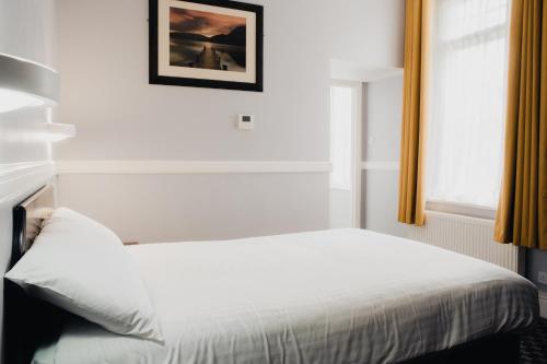 a white bed in a room with a window at San Clu Hotel, Bar & Brasserie in Ramsgate