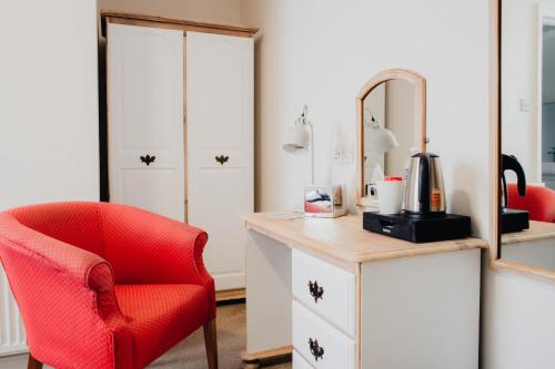 a red chair sitting next to a desk with a mirror at San Clu Hotel, Bar & Brasserie in Ramsgate