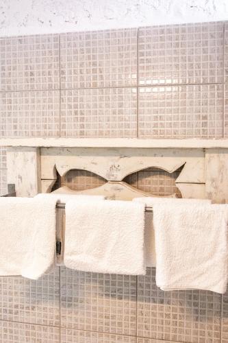 a shelf on a tiled wall with two towels at Brunis Apartments in Nei Poroi