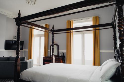 a bedroom with a four poster bed with yellow curtains at San Clu Hotel, Bar & Brasserie in Ramsgate