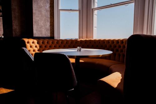 a coffee table in front of a couch with a window at San Clu Hotel, Bar & Brasserie in Ramsgate