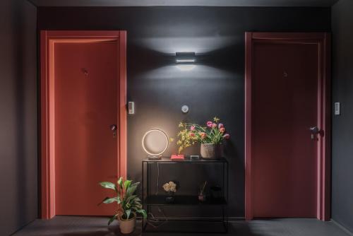 a hallway with two red doors and a table with flowers at MARCANTONIO HOME ROME - Vatican - in Rome