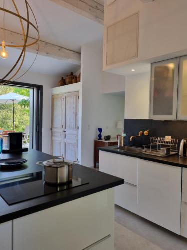 a kitchen with white cabinets and a black counter top at Mas de la Petite Jeanne in Grimaud