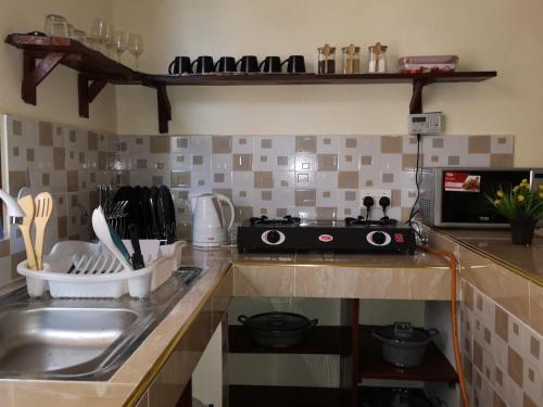 a kitchen counter with a sink and a stove at Diani Ocean View Apartment in Ukunda