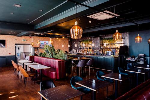 a restaurant with tables and chairs and a bar at San Clu Hotel, Bar & Brasserie in Ramsgate