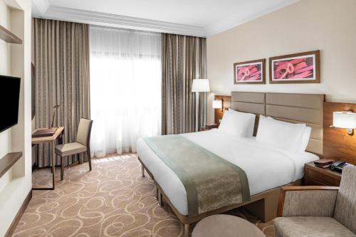 a hotel room with a large white bed and a couch at Millennium Makkah Al Naseem in Makkah