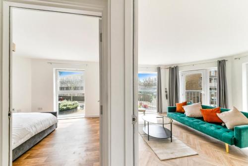 a living room with a green couch and a bed at Amazing 2 Bedroom Flat In Canary Wharf in London