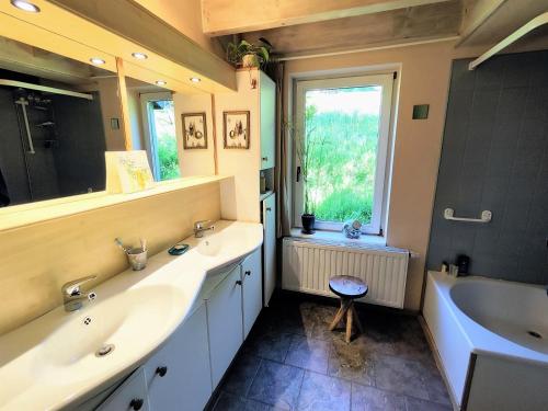 un bagno con due lavandini, una vasca e una finestra di La petite maison dans la prairie a Libin