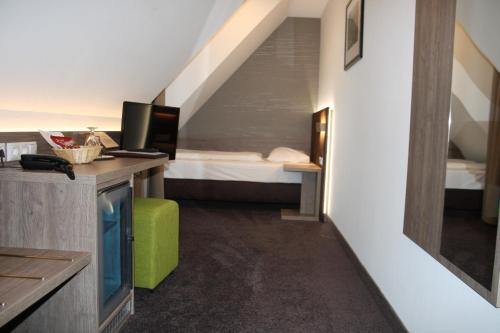 ガイゼルヴィントにあるLandhotel Geiselwindのベッド、デスク、テレビが備わる客室です。