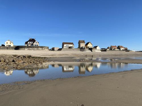 a reflection of houses in a puddle on a beach at Aparthotel Des 2 Caps in Ambleteuse