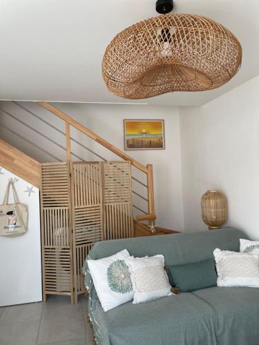 un salon avec un canapé vert et un lustre dans l'établissement Maison fonctionnelle et bien située, à Mimizan