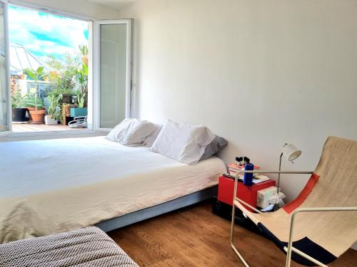 1 dormitorio con cama, ventana y silla en Sunny Terrace in Modern Flat with AC, en París