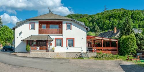 a large white house with a porch on a street at Penzion V Údolí in Hodkovice nad Mohelkou