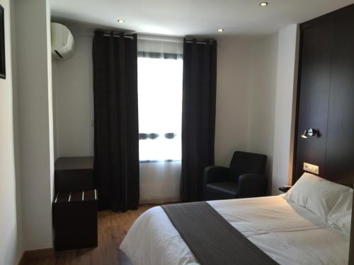 1 dormitorio con 1 cama, 1 silla y 1 ventana en Hotel Castillo, en Villarrobledo