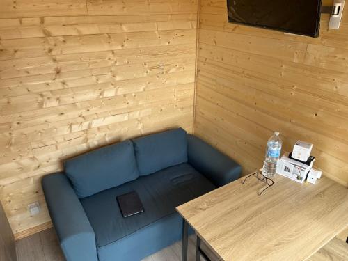 a living room with a blue couch and a table at Le Laponya - Chalets climatisés avec SPA & Borne de recharge in Bressols