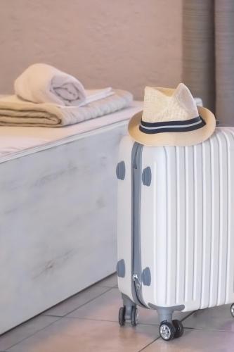 a hat sitting on a suitcase next to a bed at Brunis Apartments in Nei Poroi