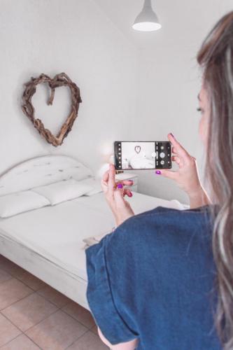 a woman is taking a picture of a heart on the wall at Brunis Apartments in Nei Poroi