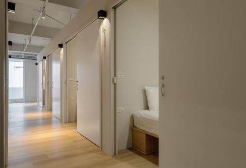 彰化市にあるTimios Inn 提米好旅の白い壁の廊下、ベッド1台が備わる客室です。
