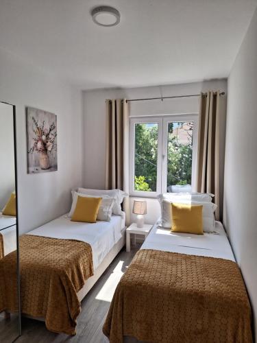 two beds in a room with two windows at Apartment Ivy in Mlini