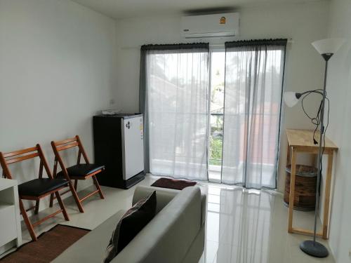 a living room with a couch and a large window at Baan7984 Rawai in Rawai Beach