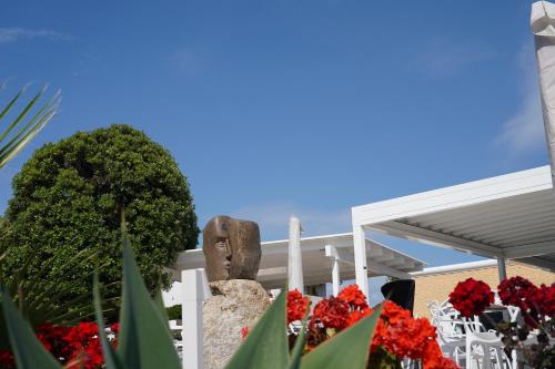 a statue in front of a building with red flowers at Hotel Parco Delle Agavi in Ischia