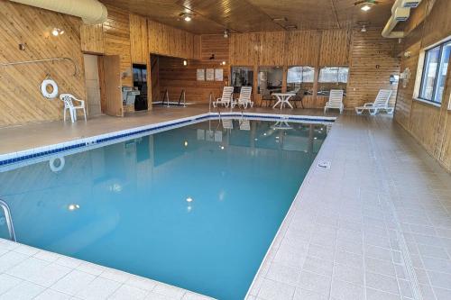 a large swimming pool with blue water in a building at AmericInn by Wyndham Tomahawk in Tomahawk