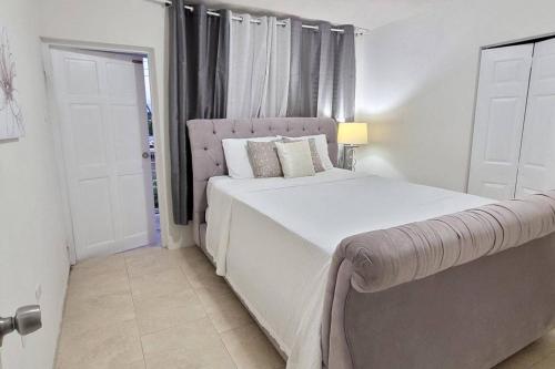 a white bedroom with a large bed and a window at De Terrace in Christ Church