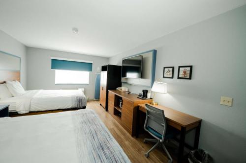 a hotel room with a bed and a desk and a chair at AmericInn by Wyndham Tomahawk in Tomahawk