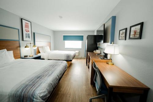 a hotel room with two beds and a desk at AmericInn by Wyndham Tomahawk in Tomahawk